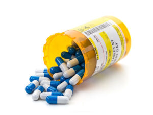 prescription prices image of a med container with blue and white capsules spilling over  