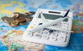 travel image of a calculator on top of a page which the world map is printed and coins on the side and a model airplane on top of the calculator